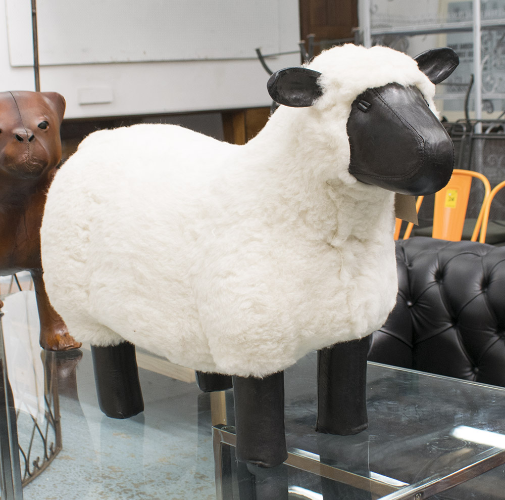 FOOTSTOOL, in the form of a sheep in black leather and wool, 75cm L.