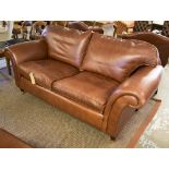 LAURA ASHLEY SOFA, with scrolling arms in a burnt sienna leather on turned supports,