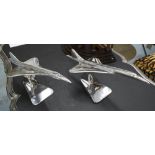 TABLE ORNAMENTS, a pair, of concorde in chromed metal on stands, 46cm L.