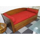 TRUNDLE DAY BED, by Bernard Siguier, with red bolster cushions, 220cm L x 97cm W x 80cm H.
