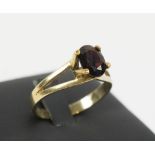 9CT GOLD DRESS RING, with open shoulders, set a facetted garnet.