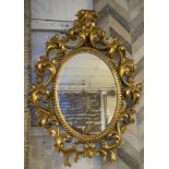 WALL MIRROR, Florentine giltwood with oval plate and scrolling leaf border, 69cm H x 54cm W.