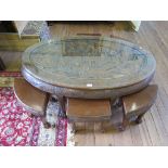 A Chinese carved hardwood low table and six stools, the oval top carved with a court scene, the