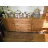 An Ercol ash sideboard with three drawers flanked by cupboard doors, 55cm wide, labelled