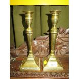 A pair of George III style brass candlesticks of turned tapering form on square beaded bases, 24cm