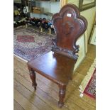 A Victorian mahogany hall chair, the carved shaped back with cartouche over a solid seat and