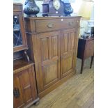 An Edwardian walnut cabinet, with one long drawer over a pair of panelled doors on a plinth base,
