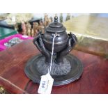 A 19th century bronze inkwell in the form of two hands holding an urn, on an oval base. 16.5cms wide