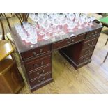 A reproduction mahogany pedestal desk, with red leather inset top above three frieze drawers, a