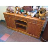 A yewwood veneer crossbanded sideboard with three drawers over open shelves flanked by cupboard