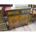 A reproduction crossbanded burr walnut cabinet, with two short drawers over a pair of cupboard doors