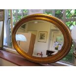 A giltwood oval mirror, the cavetto frame with tongue moulding. 87cm x 63cms