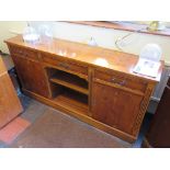 A yewwood veneer crossbanded sideboard with three drawers over open shelves flanked by cupboard