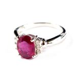 An 18 carat white gold ring set with an oval ruby with three diamonds to each side