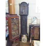 A George III ebonised oak longcase with later carving, enclosing an arched brass dial with gilt