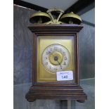 An Edwardian walnut table alarm clock surmounted by twin bells with silvered chapter ring. 25cm high