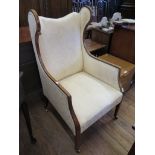 An Edwardian boxwood strung mahogany wing armchair, the scroll wings above straight arms and