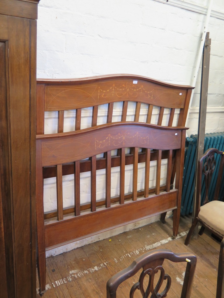 An Edwardian inlaid mahogany pair of bedends, the shaped tops over husk swag and ribbon