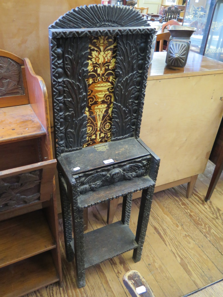 A carved oak stand, with Minton tiles depicting a foliate urn motif, with mask carved drawer and