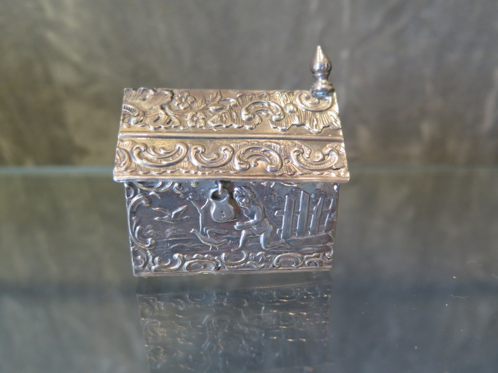 A Continental silver box in the form of a house decorated in relief with a young boy chasing