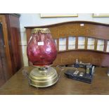 A Victorian brass oil lamp, with tulip shape cranberry glass shade 42cm high and a 'Vulcan'