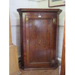 A George III oak and mahogany corner cabinet, the dentil cornice over a panelled door with inlaid