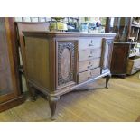A 1920s oak sideboard, with four central drawers flanked by scroll carved walnut panelled doors on