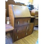 A 1930's walnut bureau, the sloping fall over three drawers beside a compartment and cupboard