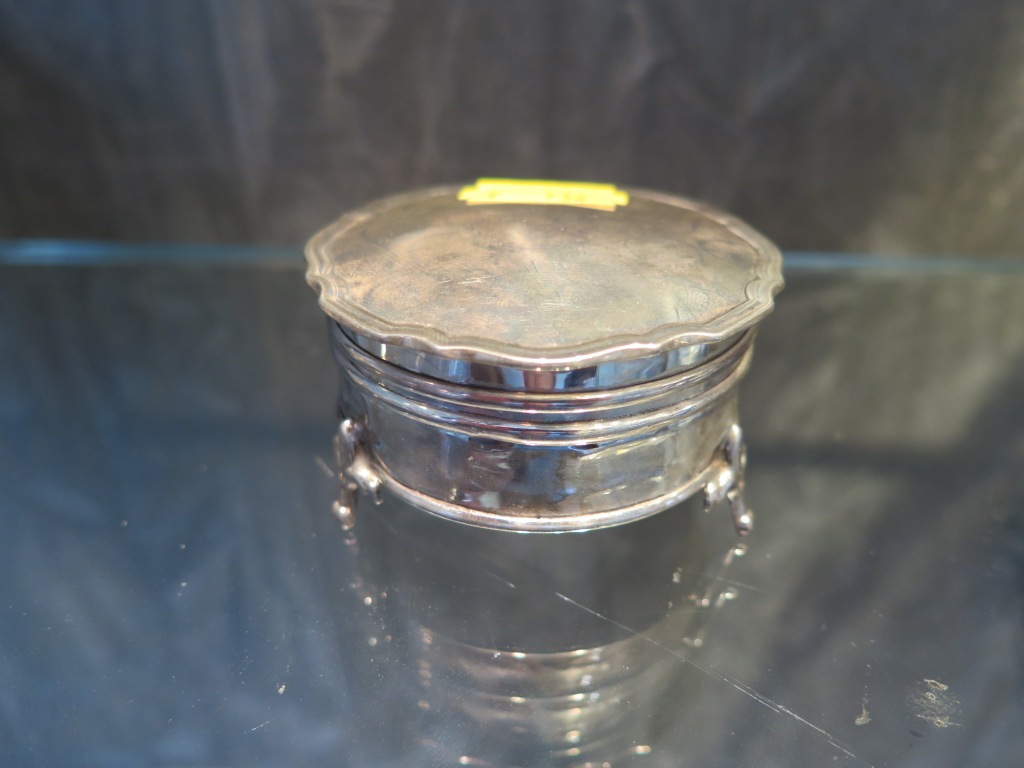 A round silver trinket box on three pad feet