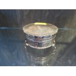 A round silver trinket box on three pad feet