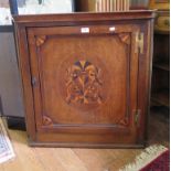 A George III oak offset corner cupboard, the panelled door with inlaid spandrals and central oval