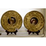A pair of German porcelain portrait plaques, mounted in brass floral scroll frames, 26cm diameter