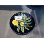 A Moorcroft Buttercup pattern circular pin tray, blue ground, impressed marks, monogrammed S.E. 12cm