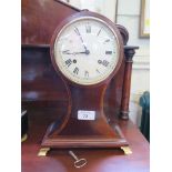 An Edwardian crossbanded mahogany waisted mantel clock with white dial and brass ogee feet, the twin