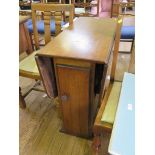 A 1930's oak drop leaf table with storage cupboard beneath 76cm wide, and a pair of oak dining