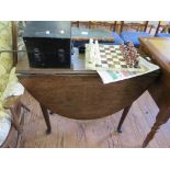 A George III oak dropleaf table, the oval top over an ogee carved frieze and turned tapering legs