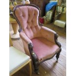 A Victorian mahogany spoon-back gentleman's armchair with scroll arms and turned tapering legs on