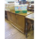 A G-Plan style oak sideboard with three panelled doors and two drawers on later castors 130cm wide