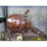 A carved hardwood elephant pushing logs, 25cm high