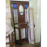 A 1930s stained beech hall stand, with blue glass panels and oval mirror over a drawer and