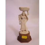 A late 19th century/early 20th century ivory figure of an Anglo-Indian woman carrying a basket on