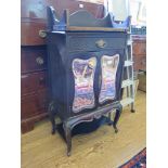 An Edwardian ebonised and mirrored music cabinet, the raised swan neck back over a drawer and pair