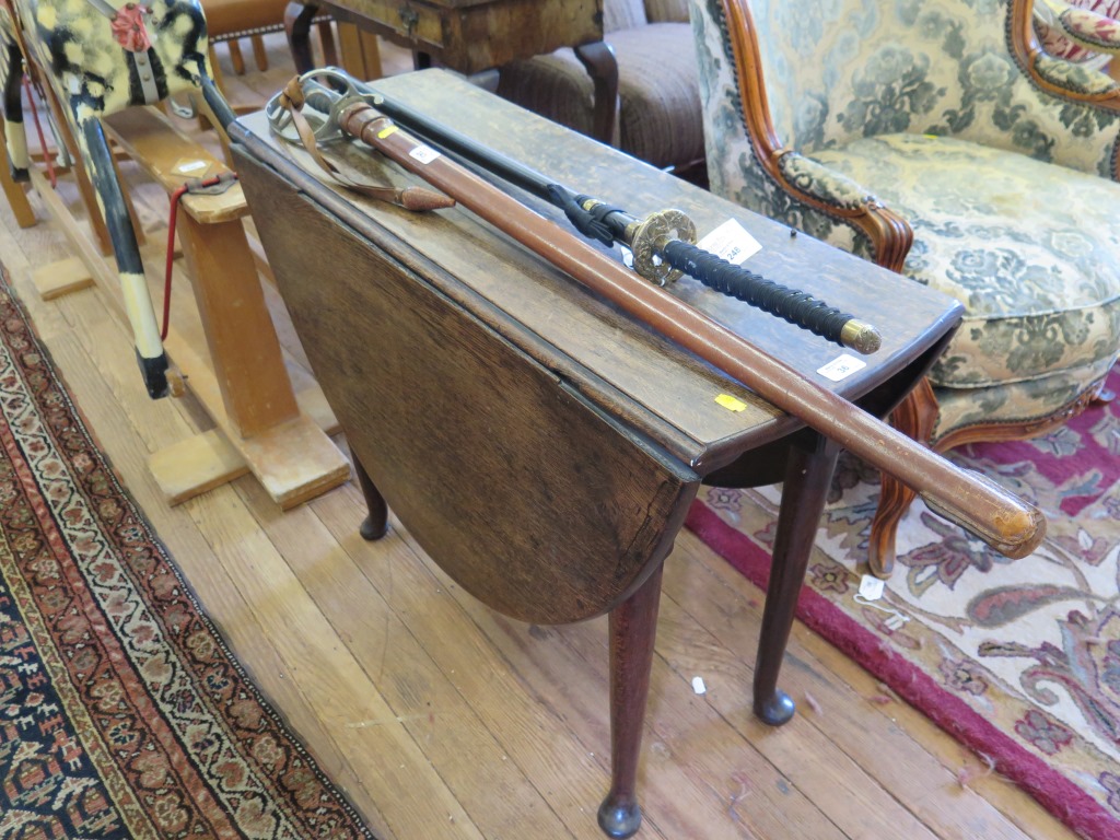 A George III oak dropleaf table, the oval top over an ogee carved frieze and turned tapering legs