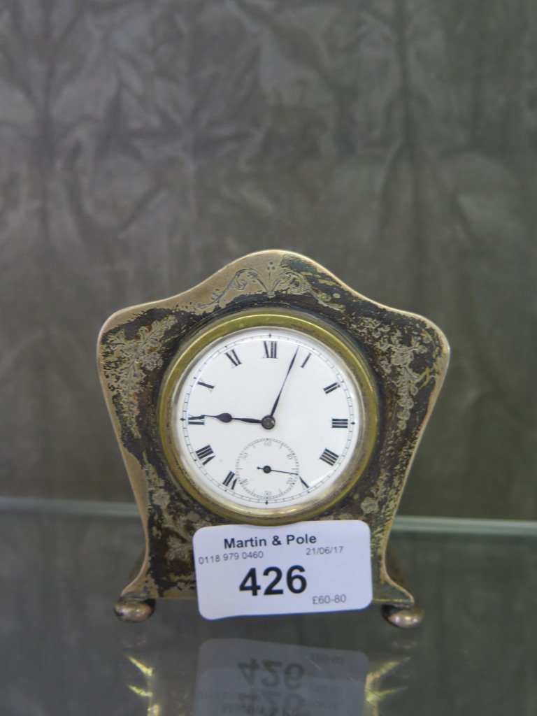 A silver cased bedside clock with brightcut decoration to case