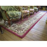 An Indian wool carpet, the red ground with all over foliate and floral design within an ivory