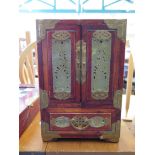 A Chinese hardwood and brass bound table cabinet, with pierced green jade panels, the cupboard doors