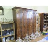 A 1930s triple door flame mahogany wardrobe, the cavetto moulded cornice over the three doors, one