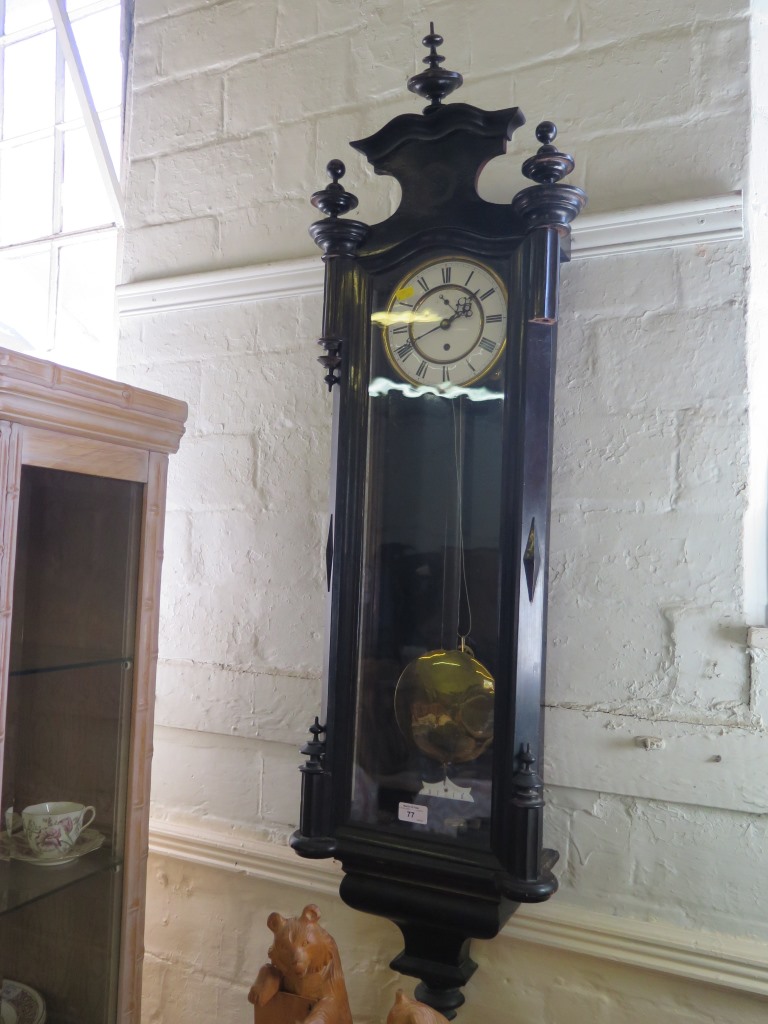 An ebonised Vienna type wall clock, with enamelled dial, shaped pediment and moulded base, single