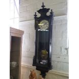 An ebonised Vienna type wall clock, with enamelled dial, shaped pediment and moulded base, single