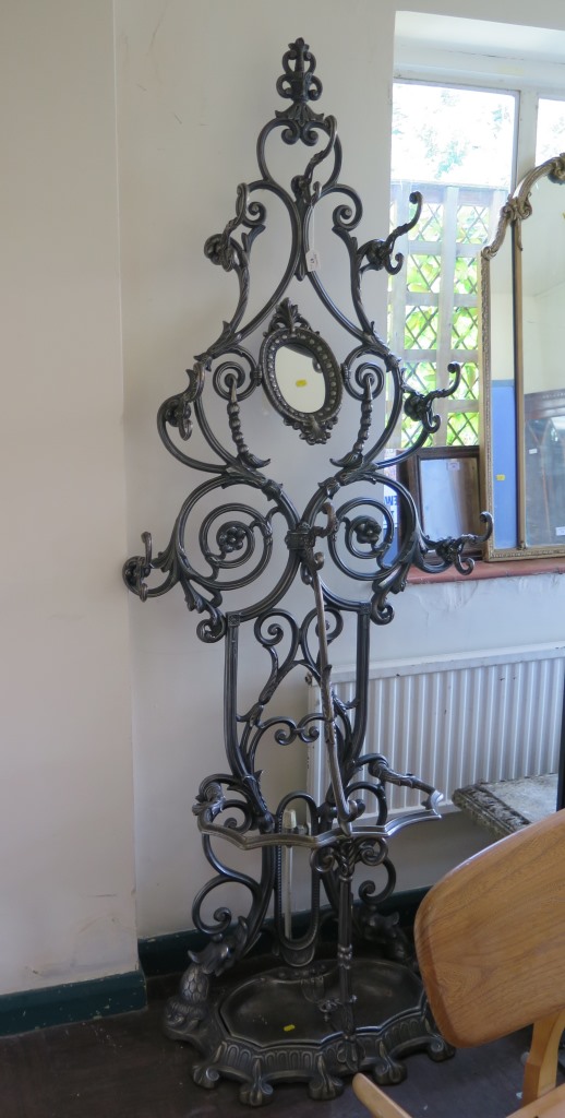 A Victorian style cast iron hall stand, of floral scroll form with hinged oval mirror and umbrella